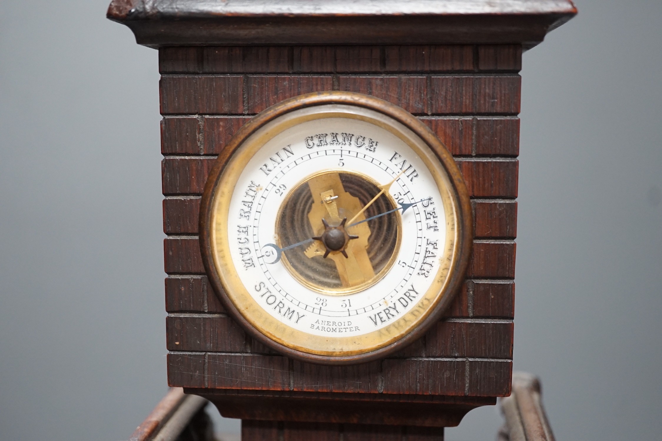 A late Victorian carved oak 'lighthouse' combined mantel timepiece and barometer, signed Frank Flower, St James' St, S.W, Height 53 cm